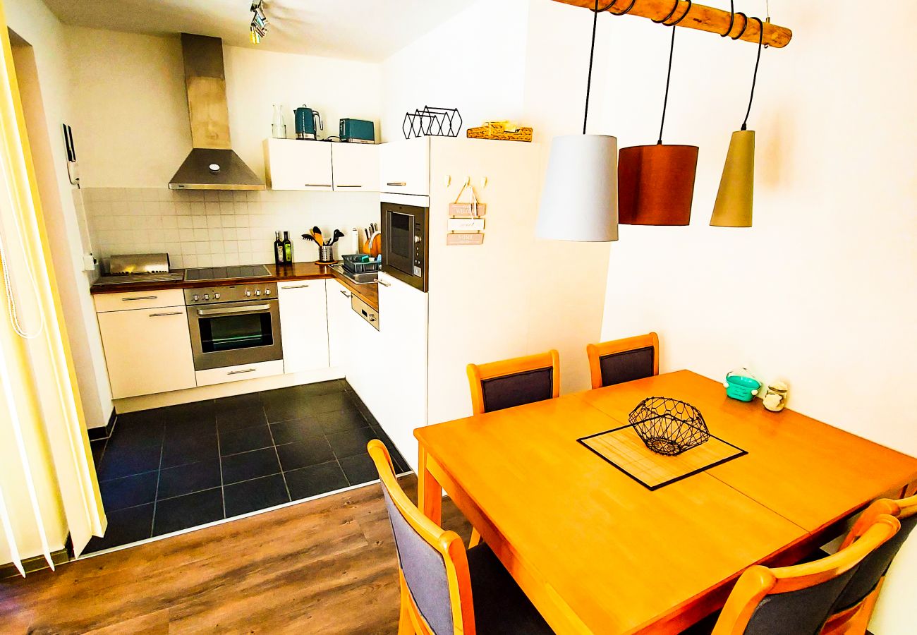 On one side you can see the dining table and behind it is the fully equipped kitchen.