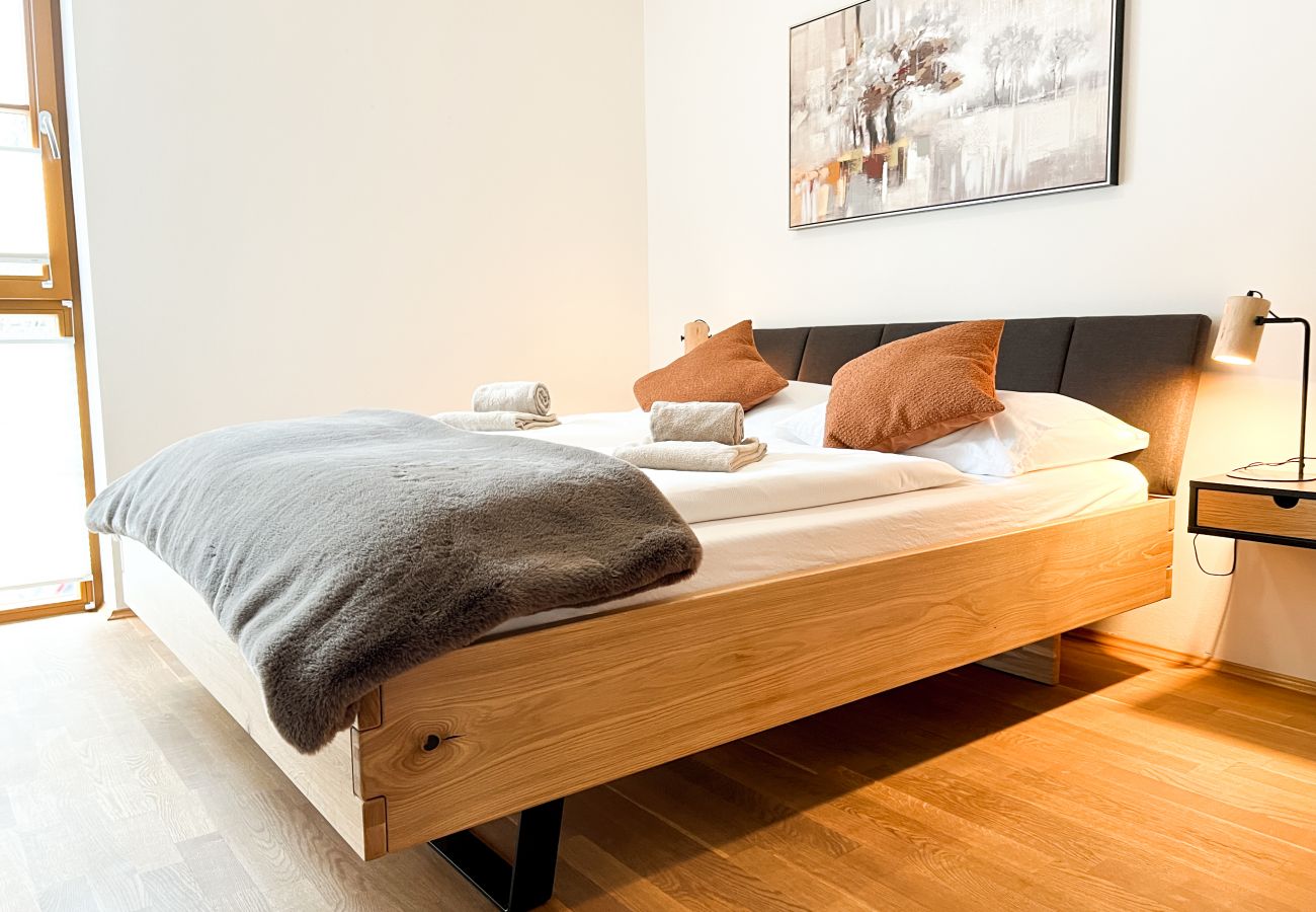 The master bedroom is modern in shades of brown and has plenty of blankets, pillows.