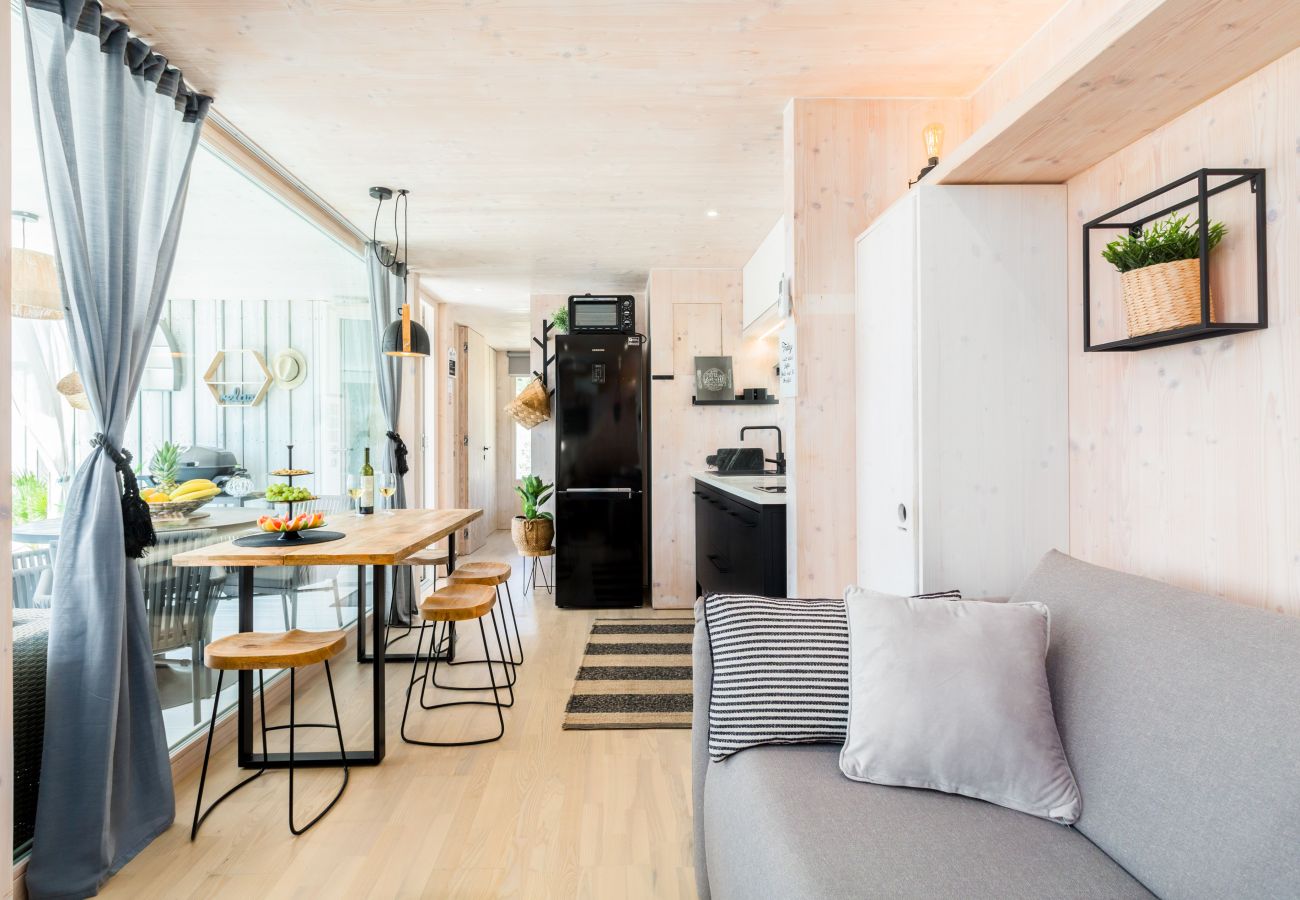 Living area with large wooden table, rustic chairs, Scandinavian kitchen and views of the terrace and sea