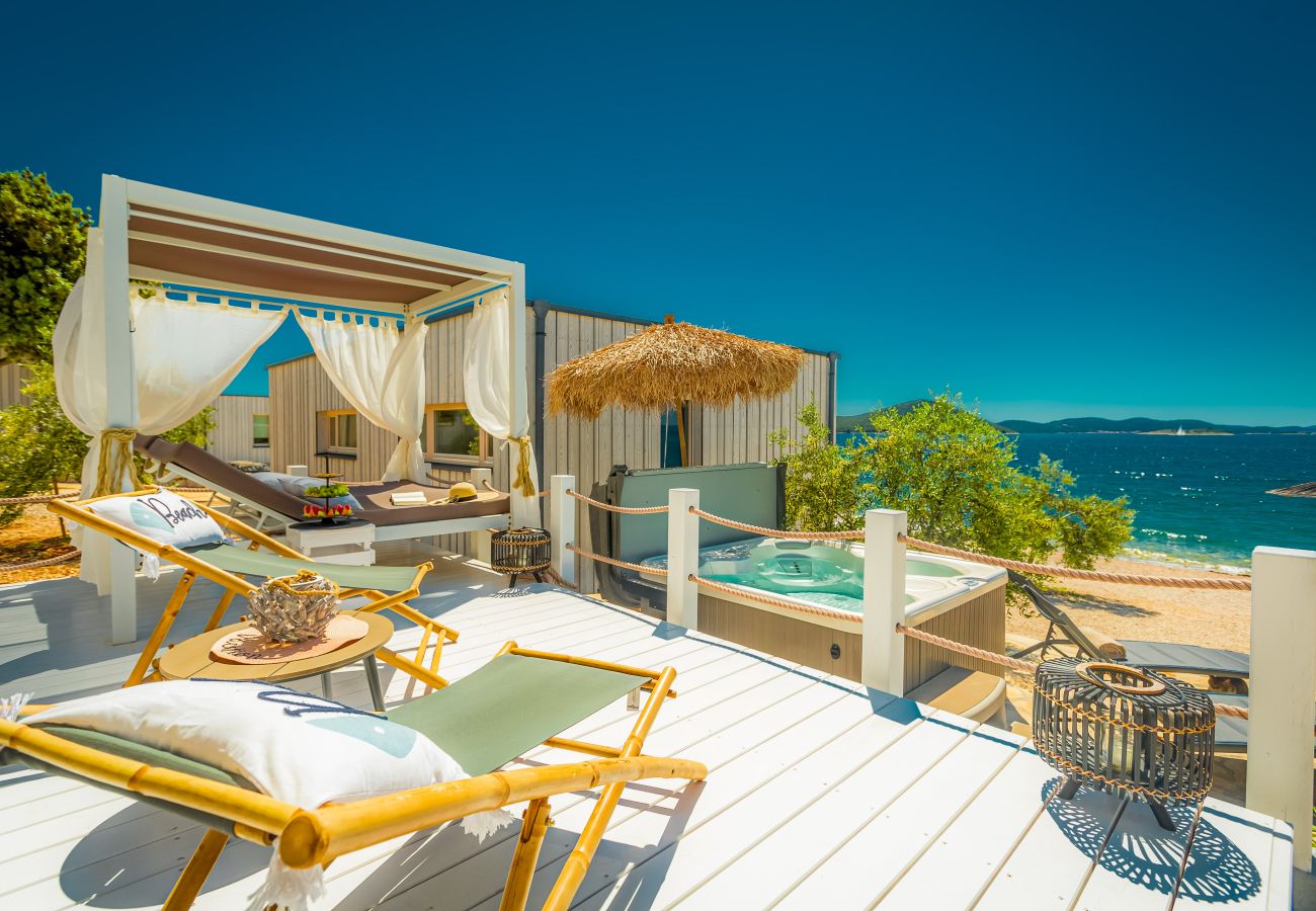 Luxuriöse Strandterrasse mit Liegestühlen und Whirlpool mit Meerblick unter blauem Himmel